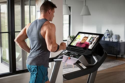 Man using a treadmill with a screen displaying virtual training.