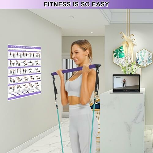 Woman using a Pilates bar for exercise in a modern home setting with a workout guide and laptop.